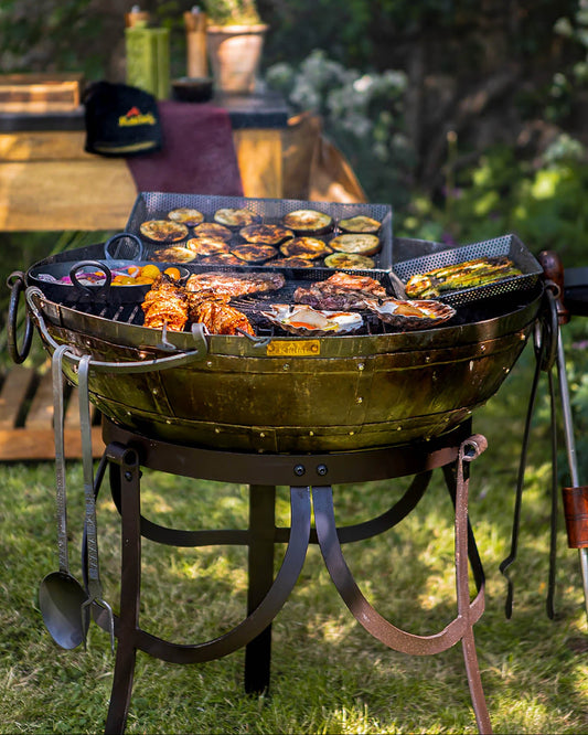 Medium sized BBQ fire pit with Kadai grill cooking meat, vegetables and seafood in a garden setting