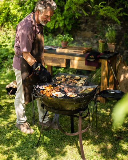 Medium BBQ fire pit with grill cooking meat, vegetables on a Kadai barbecue in a garden setting