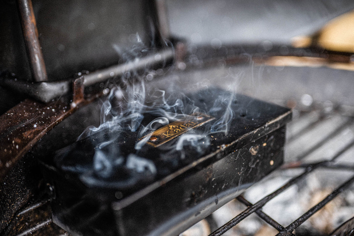 Smoking black metal smoker box on a grill.