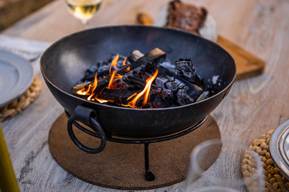 Outdoor BBQ table with Kadai fire bowl lit with glowing embers and flames at centre
