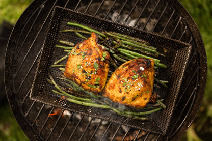 Cooked chicken and green beans on a grill tray on the top of a BBQ