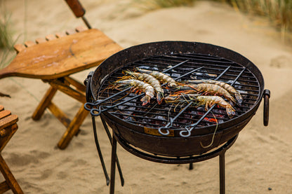 Portable BBQ with shrimp on a sandy beach